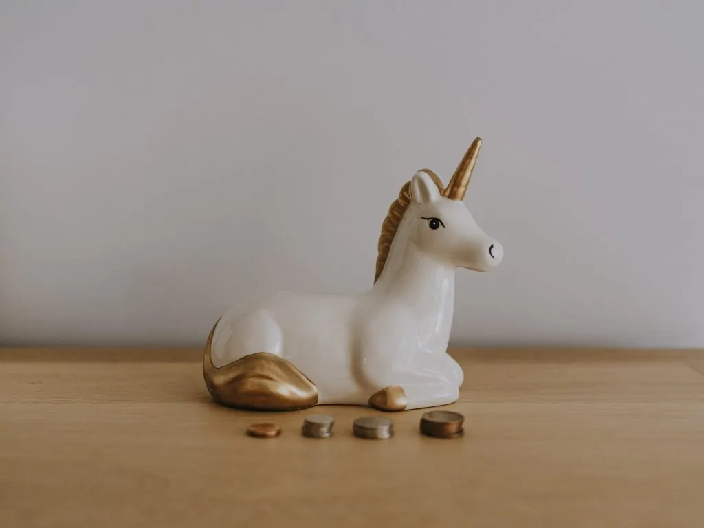unicorn money box on a desk with coins