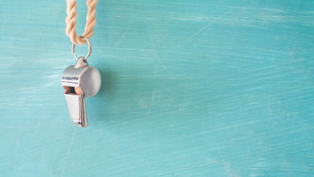 A whistle hanging on a light blue wall