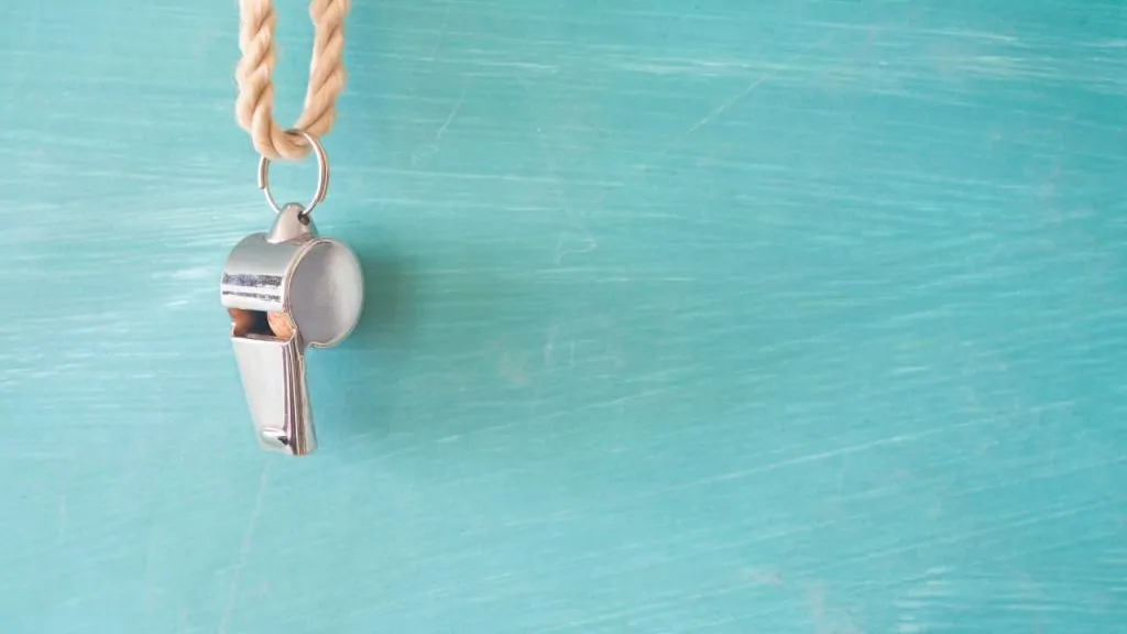 A whistle hanging on a light blue wall